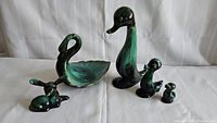 Five Blue Mountain Pottery ceramic animal figurines arranged on a white surface against a white backdrop. Visible are three ducks, a swan, and a deer, showing front views and relative size differences.
