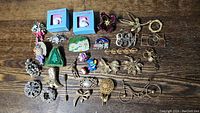 Full lot of mostly vintage brooches arranged on wooden surface showing variety of designs including floral, animal shapes, and novelty pieces.