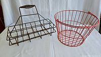 Photo showing the metal milk bottle carrier and red wire basket side by side on white surface with light background