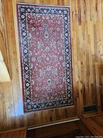 Full view of the rectangular orange, black, and gold floral-patterned area rug on a wooden floor.