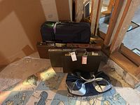Photo showing the set of four dark brown briefcases and one black Adidas vinyl duffel bag with silver handles on a floor with cartoon-printed rugs.
