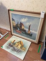 View of two nautical themed oil paintings leaning against a wall on the floor, one large framed and one smaller unframed signed by P. Salas