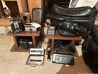 Overview of the entire lot showing all cameras, Sony video camera, vintage film cameras, cases, charger, cables, and manual