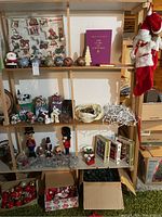 Full shelving unit displaying the Christmas decorations including nutcrackers, village houses, ornaments, stockings, and lights packed in boxes.