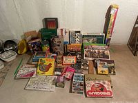 Overview of the board and educational games collection showing various boxed vintage games stacked and spread out on the floor.