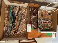 Photo of assorted costume jewelry including bangles, clip-on earrings, brooch pins, and pendants arranged in boxes.