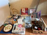 Wide view of the craft supplies laid out, including embroidery hoops, books, paints, and fabric rolls