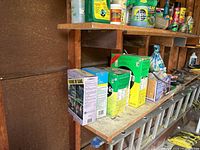 Photo showing assortment of garden chemicals and lawn food on wooden shelving.
