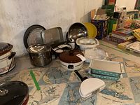 Front view of assorted kitchenware including casserole dish, mixing bowls, electric frying pan, pot, and bakeware on a patterned mat.
