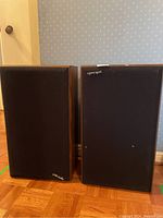 Two Polk Audio floor speakers side by side, showing full front and side wood finish