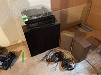 Full lot view showing Pioneer combo unit on two black Akai floor speakers, separate brown Electra speakers, and two pairs of headphones on floor.