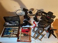 Full view of the lot showing cordless drill, flashlight, palm sander, chisels in wooden box, clamps, and soldering iron.