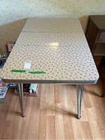 Top view of the rectangular table showing the white Formica surface with a small black floral pattern and chrome legs. Table leaf visible along center.