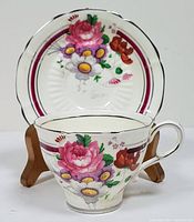 Front view of the teacup and saucer displaying detailed floral pattern and silver rim on both items.