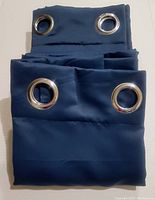 Folded navy blue blackout curtain panel showing shiny silver grommets for hanging