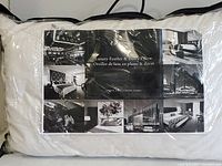 Packaged white pillow in clear zippered bag with black and white Fairmont Hotels & Resorts label showing text and hotel images.