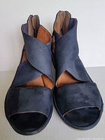 Front view of navy Clarks wedge sandals showing open toe and crisscross strap design with visible wear on toes.