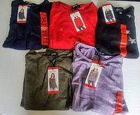 Five folded Buffalo David Bitton long sleeve knit tops for women with size Medium tags in various colors including navy, red, black with stars, olive green, and purple.