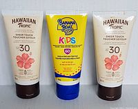Front view of three sunscreen lotion tubes: two Hawaiian Tropic Sheer Touch SPF 30 and one Banana Boat Kids SPF 60.