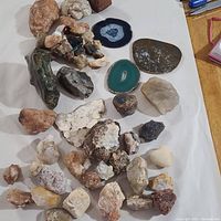 Various geode slices and mineral specimens spread on white surface, showing variety of colors and textures.