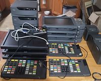 Four IBM POS computers stacked with attached multi-colored key button cash register keyboards, three Acer monitors stacked on top, two NCR receipt printers visible and assorted cords.