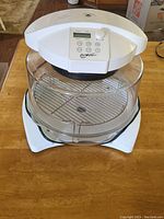 Full view of Thane Housewares Flavor Wave Oven Deluxe showing top control panel, clear glass cooking chamber, and metal rack inside.