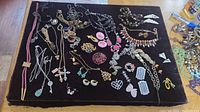 Top-down view of multiple pieces of vintage costume jewelry including Monet necklaces, earrings, brooches and bracelets arranged on a black velvet board