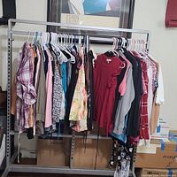 Clothing rack with 22 pieces of women's pre-owned designer clothes in various colors and patterns on hangers.
