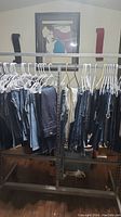 Metal clothing rack with assorted women's jeans on hangers in various washes and styles.