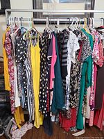 View of a rack with multiple women's dresses in various styles and colors, showing variety and quantity in the lot.