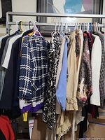 Hanging women's suit jackets in various colors and patterns on hangers on a metal rack