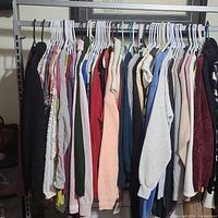 Photo of women's sweaters on hangers displaying various colors and styles, showing length and texture