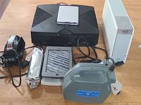 All items from the lot arranged on a table. Xbox console, Kindle, printer, oxygen machine, hand massager and ink cartridge visible.