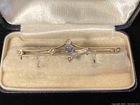 Front view of bar brooch in velvet-lined box showing design and stone placement