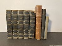 Front view of the 8 antique books showing set of 5 Plutarch's Lives and 3 other books
