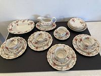 Full set of plates, cups, saucers, and gravy boat displayed on table.