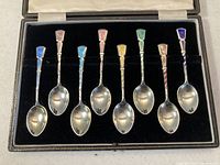 Overview of eight teaspoons arranged in fitted black velvet-lined case