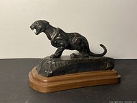 Side angle view of the bronze mountain lion sculpture showing detailed musculature and snarling expression.