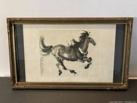 Framed Chinese ink painting of a galloping horse with black matting and glass protection.