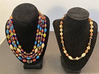 Both necklaces displayed on black busts showing overall style and design