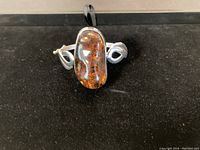 Front view of bracelet showing large amber stone and sterling silver setting with swirl details.