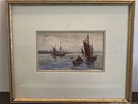 Framed original watercolour painting with several boats on water under glass and gold frame.