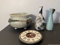 Three Raku pottery items (footed bowl, two bottle vases) and round ceramic clock face laid out together