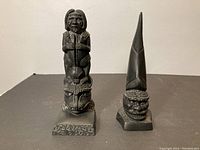 Front view of both totem sculptures displayed side by side on a flat surface.
