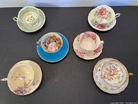 Overview of six teacups with matching saucers on black surface