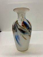 Front angled view of the white opaque vintage Italian glass vase showing colorful swirled glass design