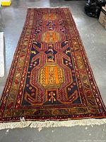 Full view of handmade Persian rug laid flat showing geometric medallion pattern and knotted fringe