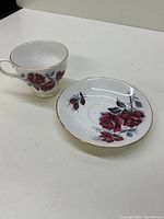 Tea cup and saucer set featuring red rose floral design and gold trim