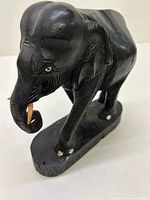 Front angled view showing detailed elephant carving, tusks, painted eyes, and base.
