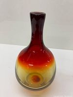 Front view showing the elongated neck and color gradient from dark red to amber and clear.